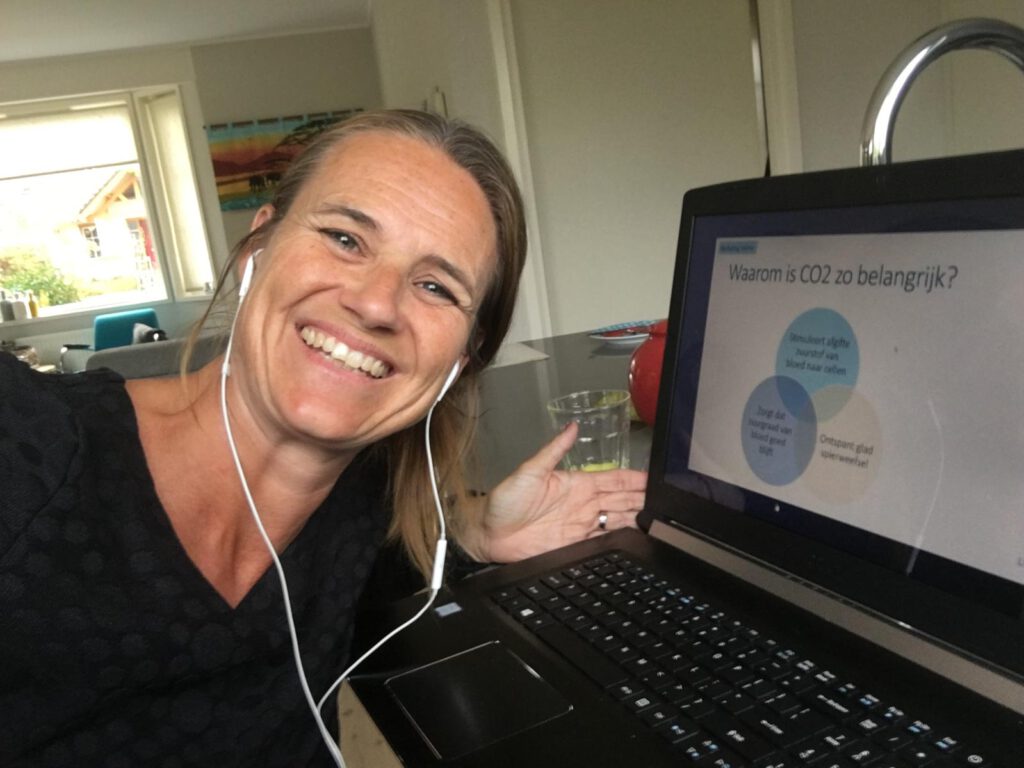 "Linda Aardema glimlacht terwijl ze achter haar laptop zit, klaar om vragen van klanten te beantwoorden voor BeweustInBeweging."