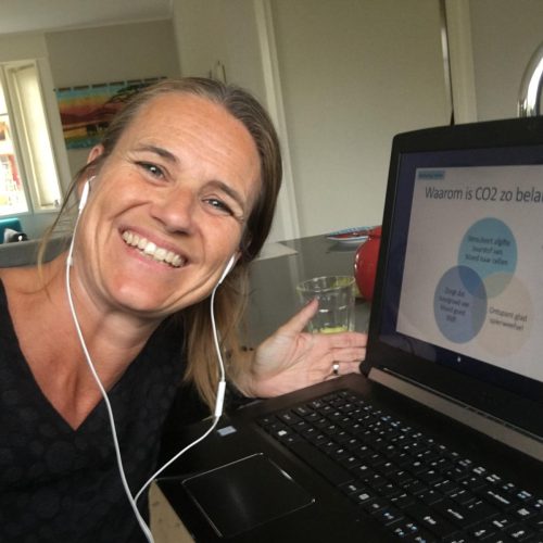 "Linda Aardema glimlacht terwijl ze achter haar laptop zit, klaar om vragen van klanten te beantwoorden voor BeweustInBeweging."